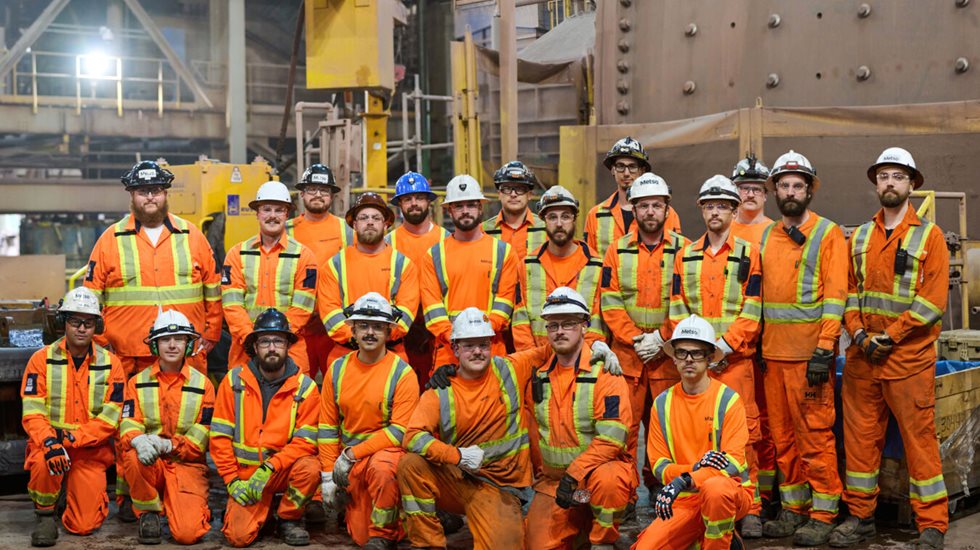 Group of Metso reline employees in PPE standing together in from of a grinding mill