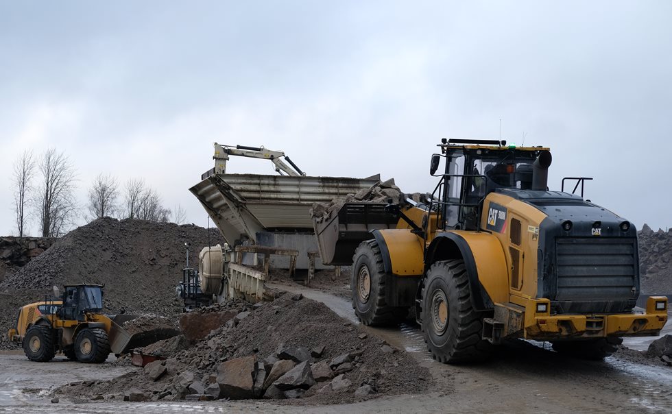 Both feeding the crusher and cleaning the pile under the conveyor have been executed with Caterpillar 980 series wheel loaders.