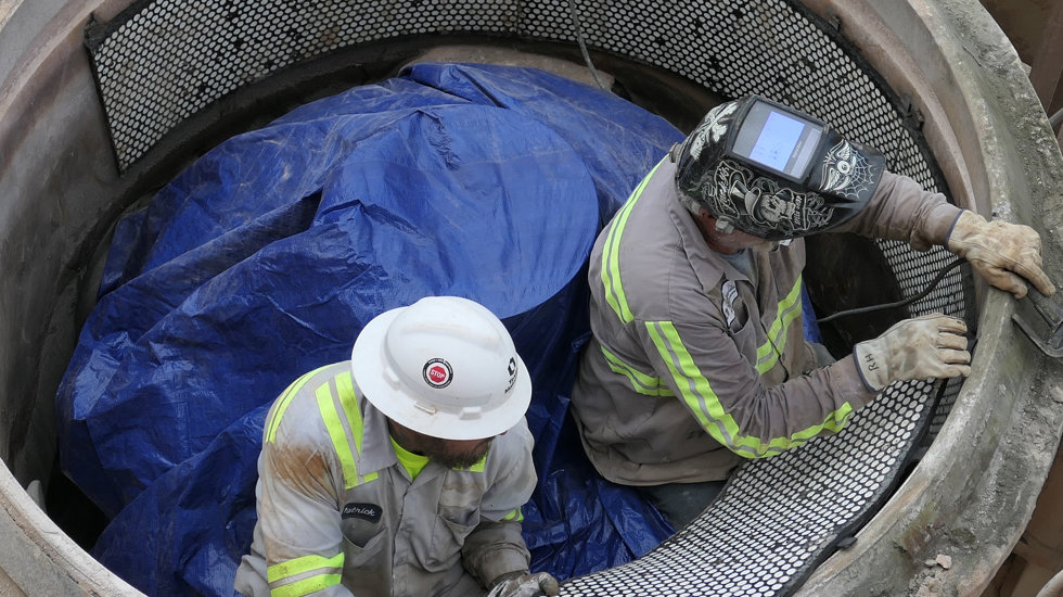 Two men working on crusher wear parts.
