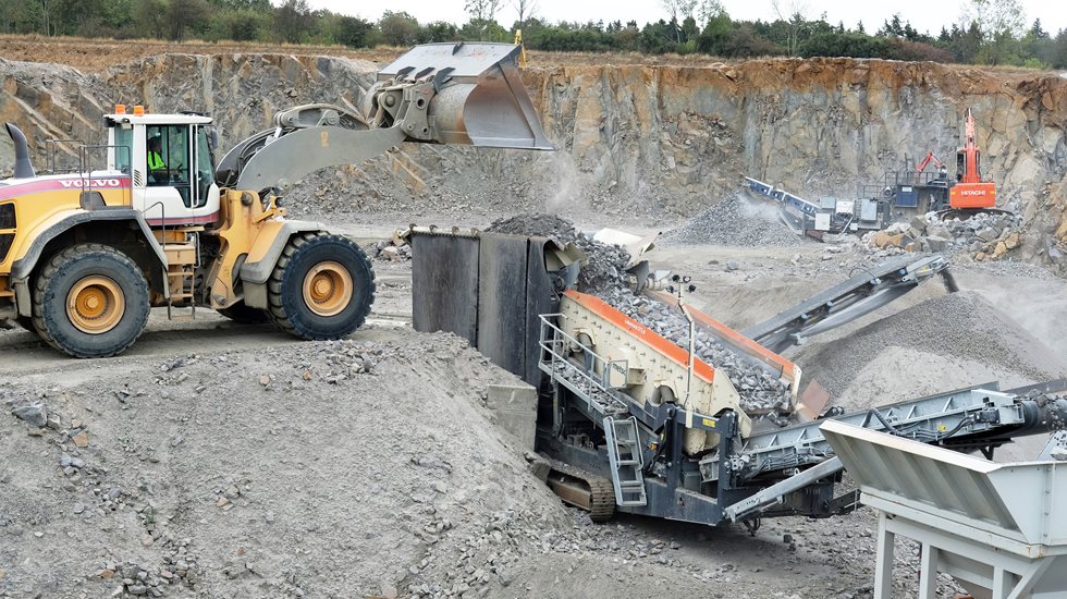 An excavator feeding a Lokotrack at a quarry.