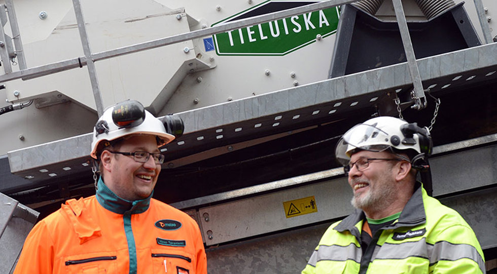 Kaksi hymyilevää miestä seulan vieressä.