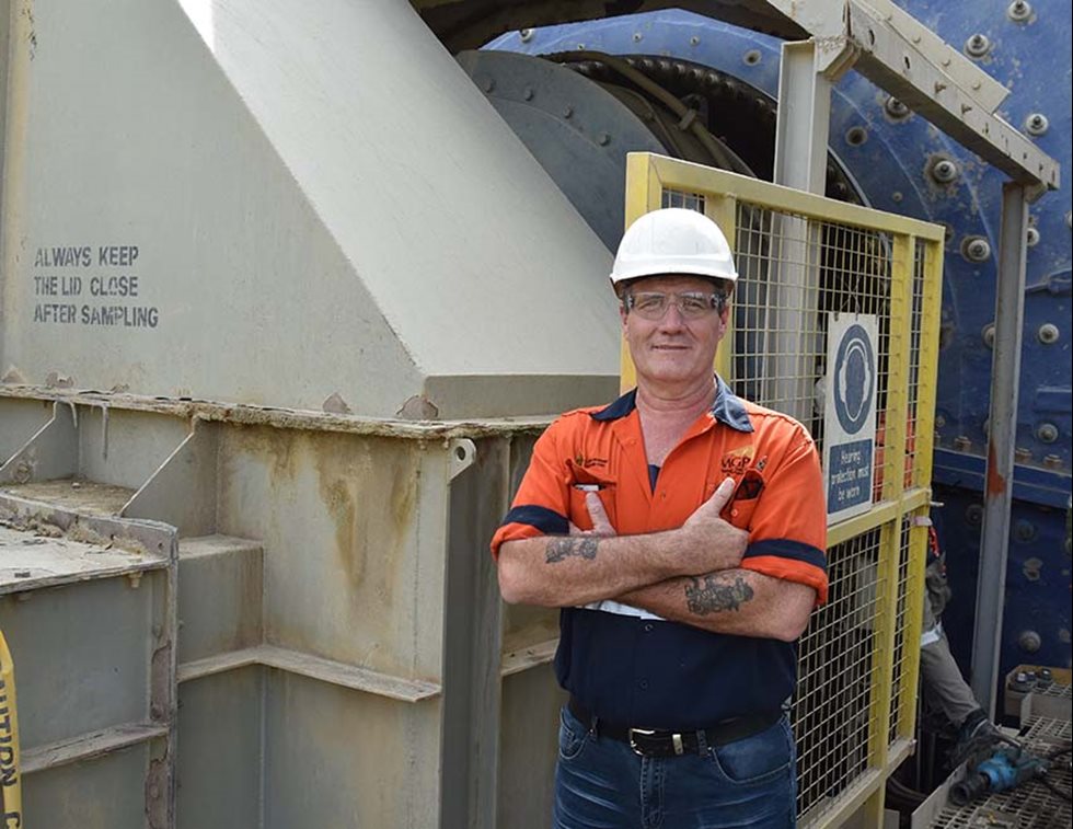 A man poses to the camera with a ball mill in the background.