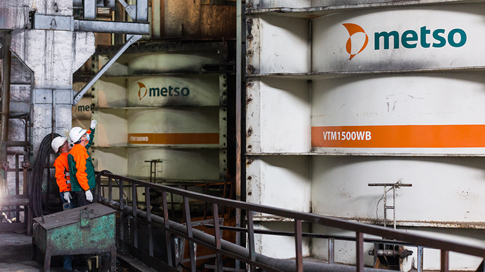 Two people looking at Vertimill vertical mills at a mine site.
