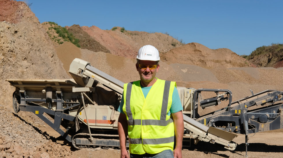 A man standing at a quarry with a Lokotrack in the background.