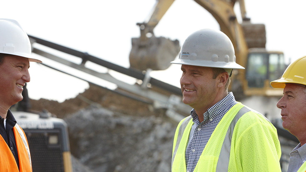 One men on the left and two on the right talking at a crushing and screening site. 