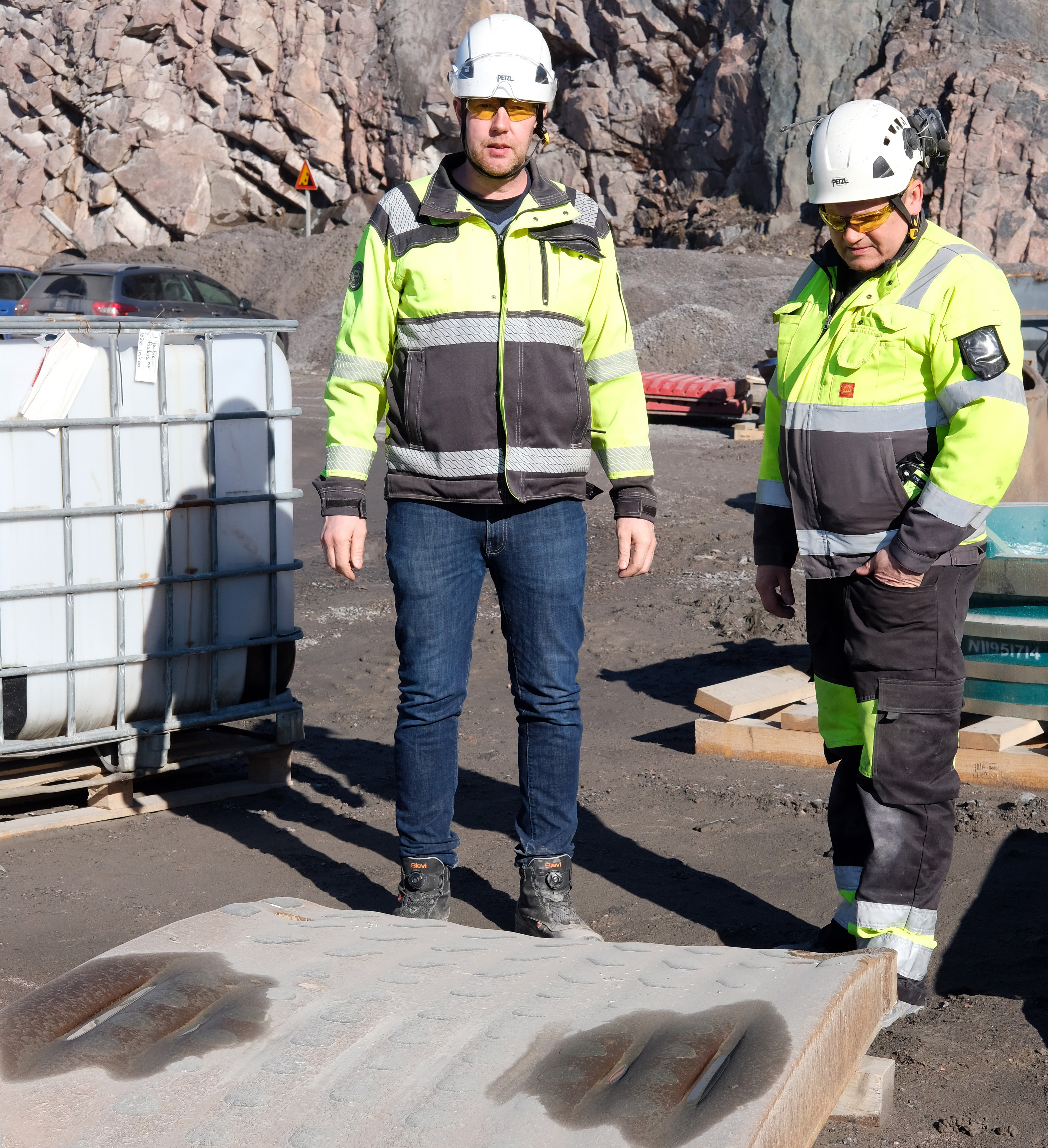 Two men at a quarry behind a jaw wear plate in the ground.