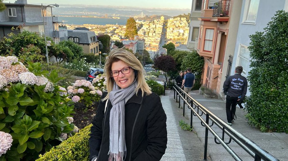 Paula Peres standing on the street, smiling at the camera.