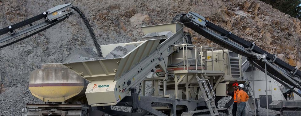 Two men next to mobile crusher with Barmac VSI crusher.