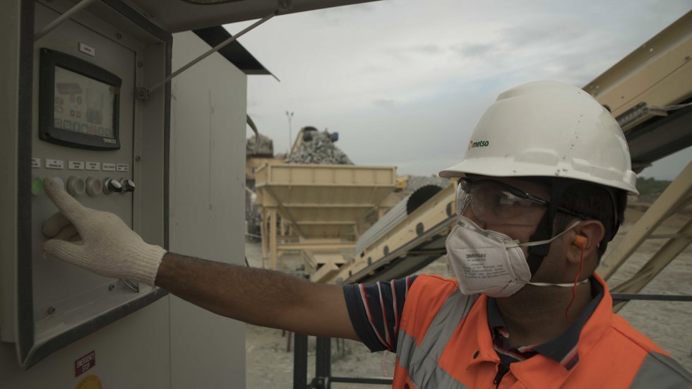 A man at a quarry handling the control buttons of mobile crushing equipment. 