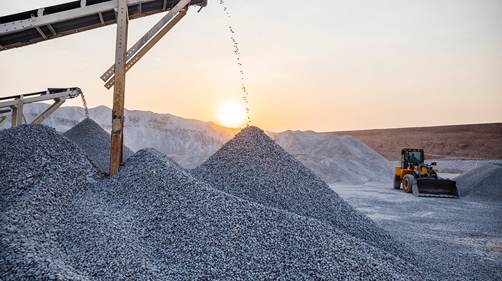 A view at the quarry with sun setting behind and aggregate falling to a pile. 