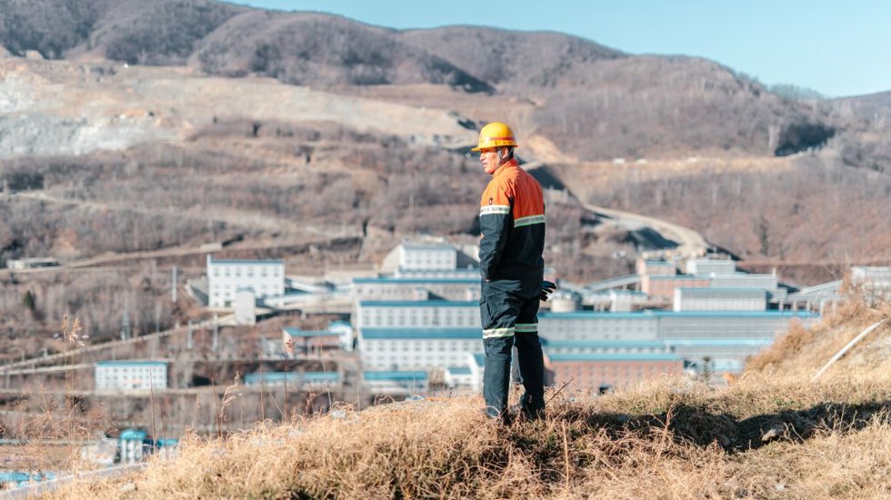 Hombre mirando hacia abajo desde una pequeña colina, hacia el sitio minero de Hunchun Zijin.