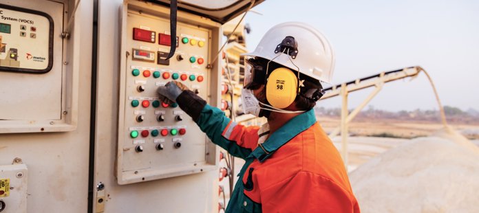 A man operating a machinery panel wearing personal protective equipment